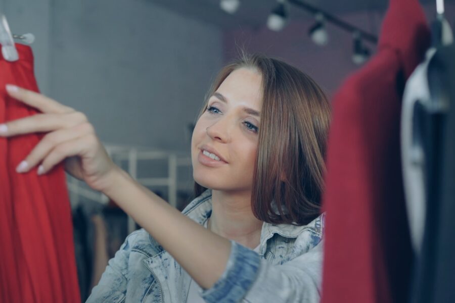 Woman choosing colorful clothes wardrobe rack