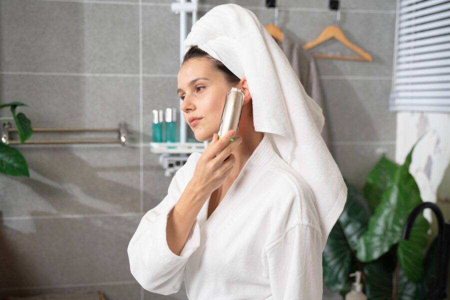 Woman spraying perfume bottle bright bathroom