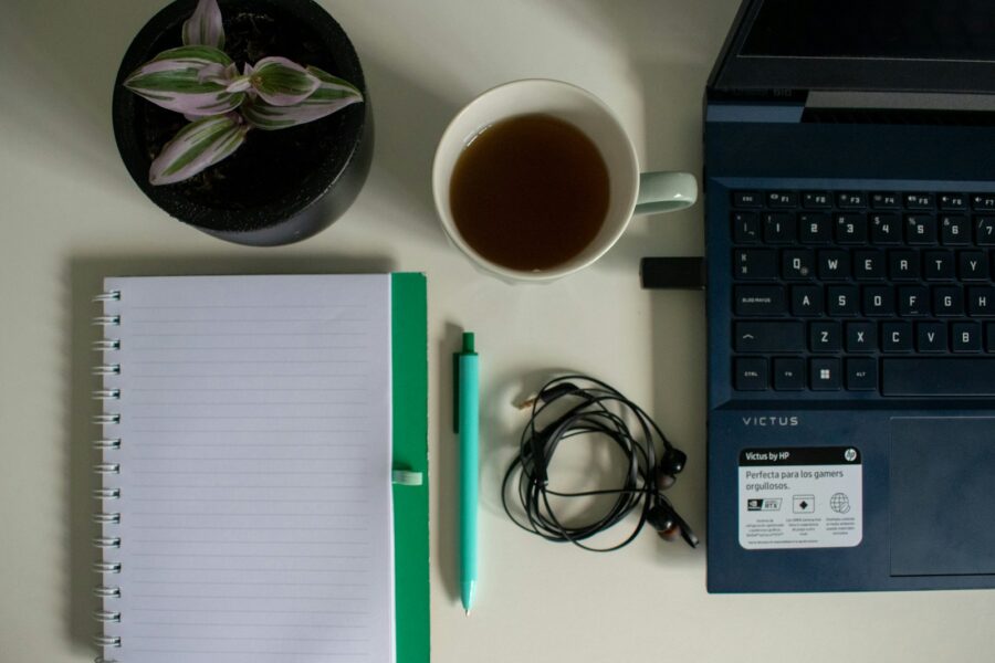 Open notebook laptop pen coffee mug desk