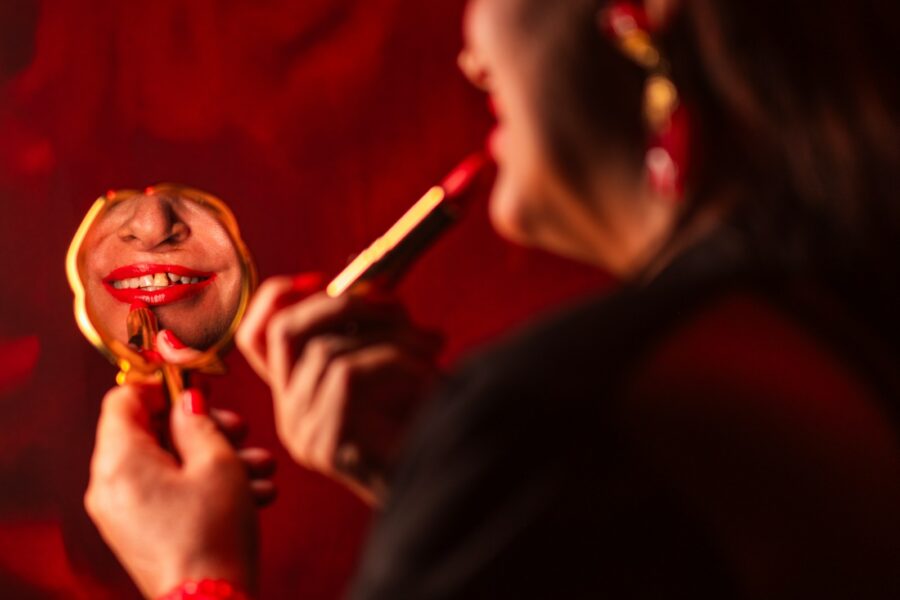 Woman applying red lipstick mirror close-up