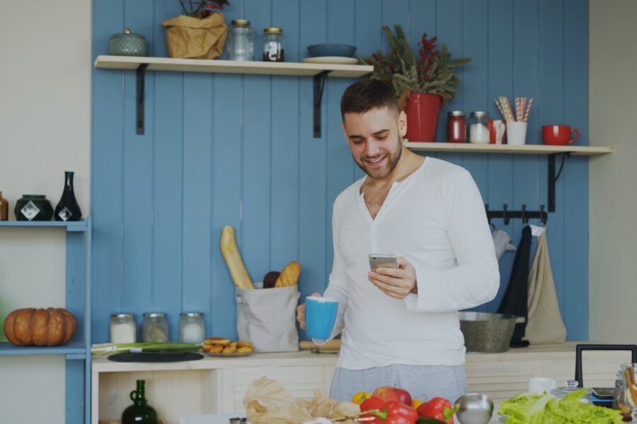 Person holding smartphone kitchen table notebook coffee