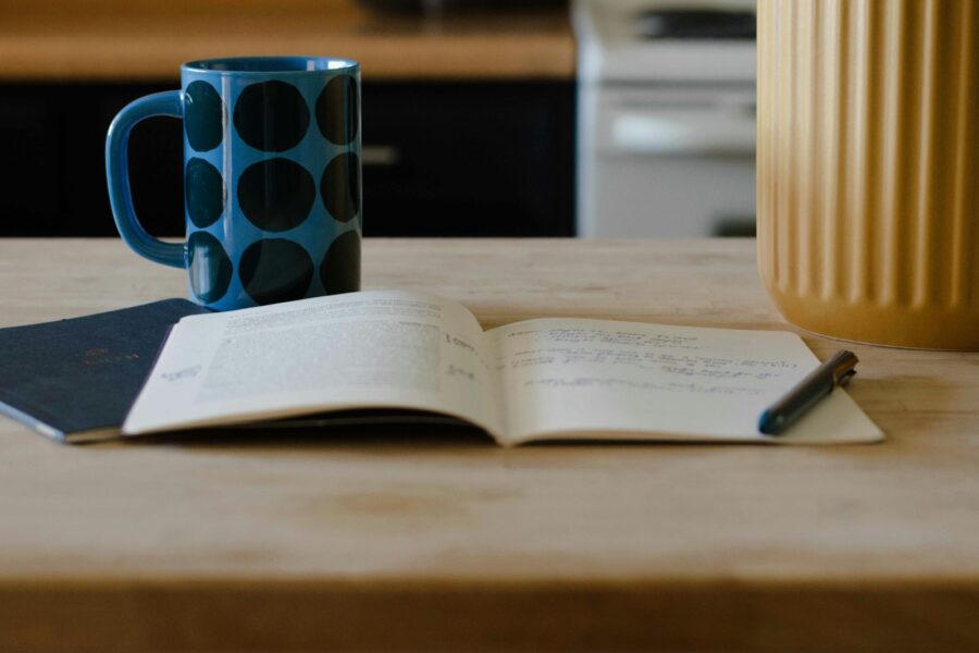 Open notebook pen cup tea cozy table
