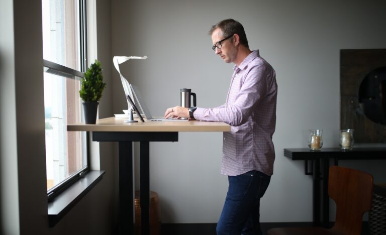Office worker stretching standing desk window