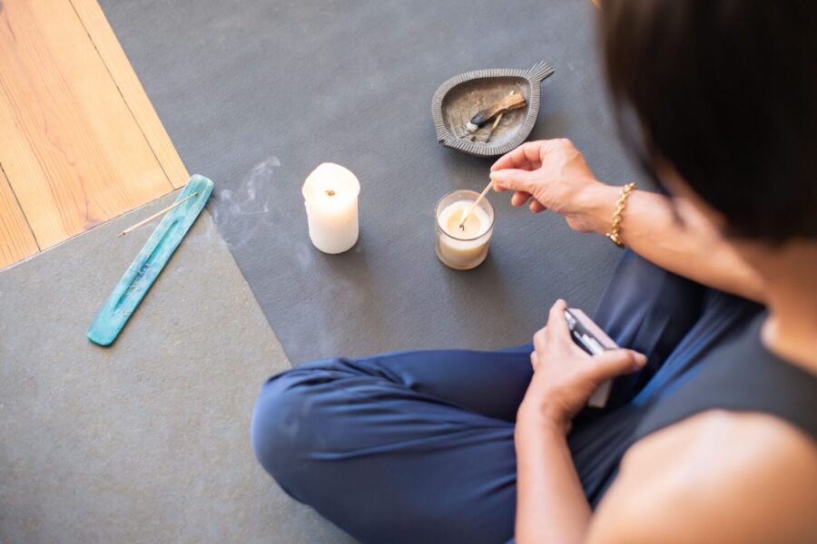 A person engages in a calming ritual with candles and palo santo, creating a serene atmosphere.