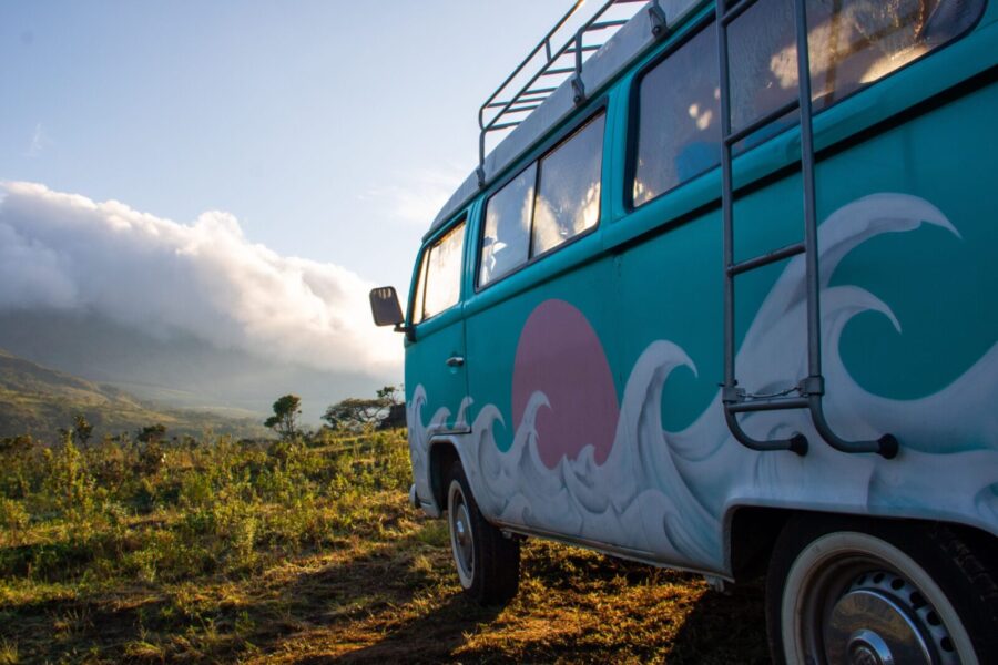Colorful vintage camper van in a scenic outdoor landscape at sunrise.